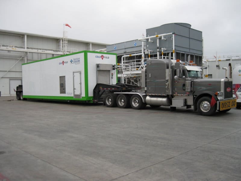 A large truck is pulling a trailer with a green and white trailer.